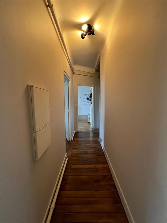 Couloir étroit en parquet desservant plusieurs bureaux